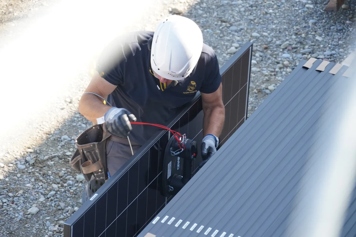 Ein Bauarbeiter montiert eine Halterung an das Solarmodul. 